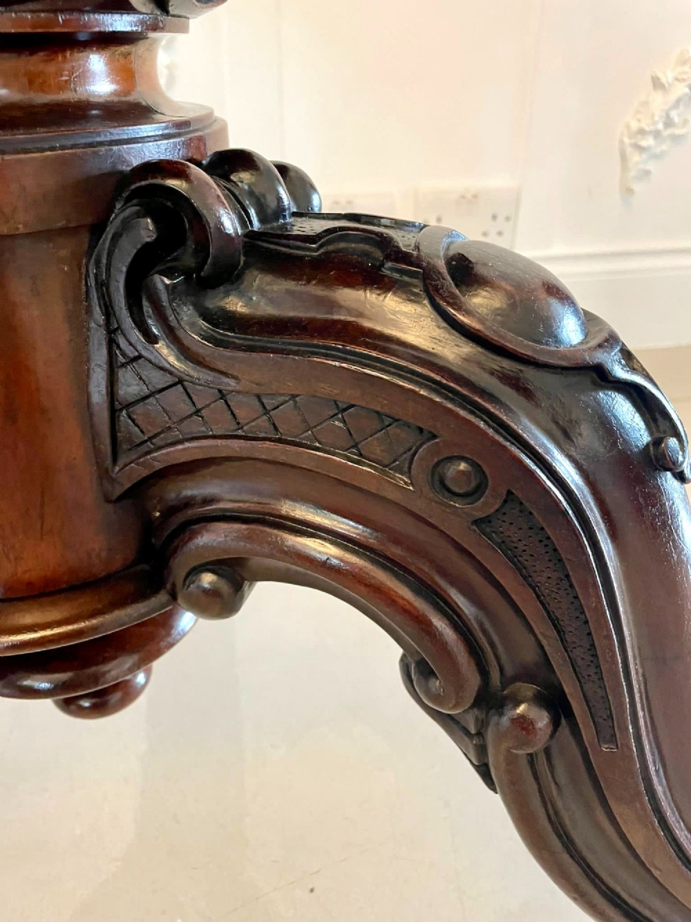 An Early Victorian octagonal rosewood tilt-top centre table with a highly figured grain surface resting on a carved pedestal base with scroll feet. View X