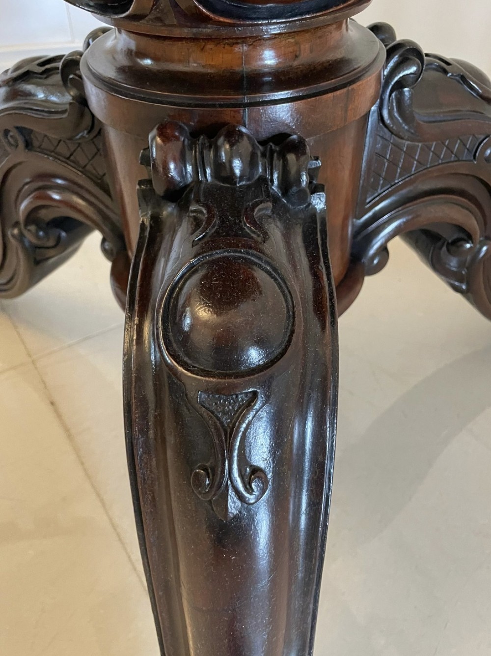 An Early Victorian octagonal rosewood tilt-top centre table with a highly figured grain surface resting on a carved pedestal base with scroll feet. View XI