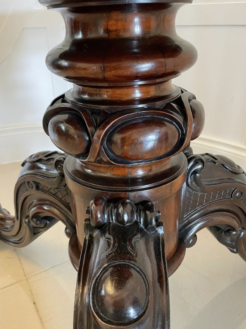 An Early Victorian octagonal rosewood tilt-top centre table with a highly figured grain surface resting on a carved pedestal base with scroll feet. View XIII