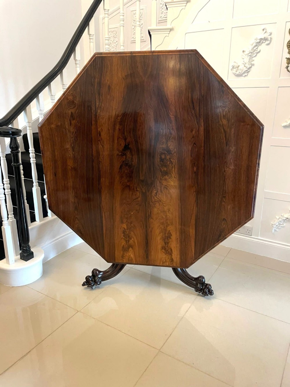 An Early Victorian octagonal rosewood tilt-top centre table with a highly figured grain surface resting on a carved pedestal base with scroll feet. View XV