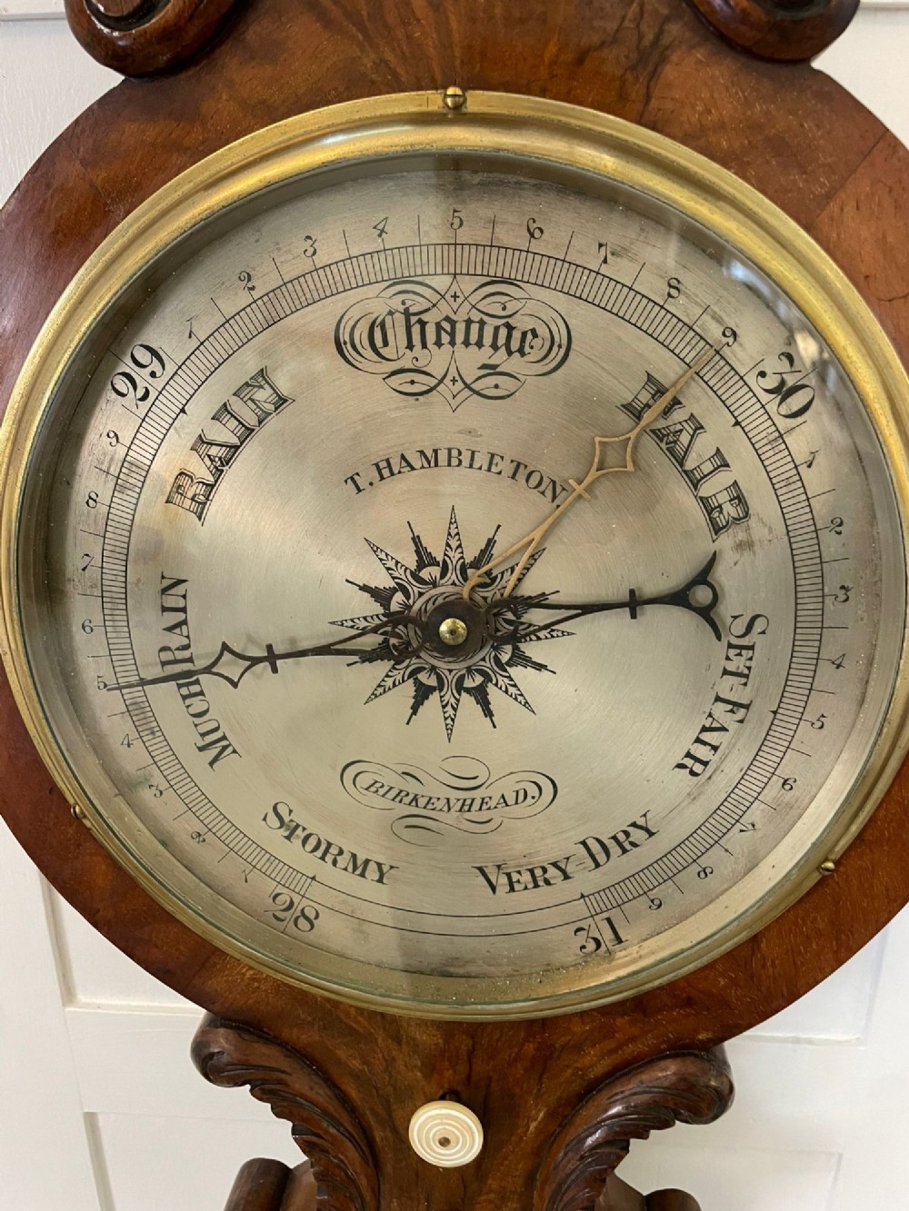 Victorian wall-mounted banjo barometer crafted from carved burr walnut featuring an upper glass thermometer gauge and a lower silvered dial in a brass frame. View II