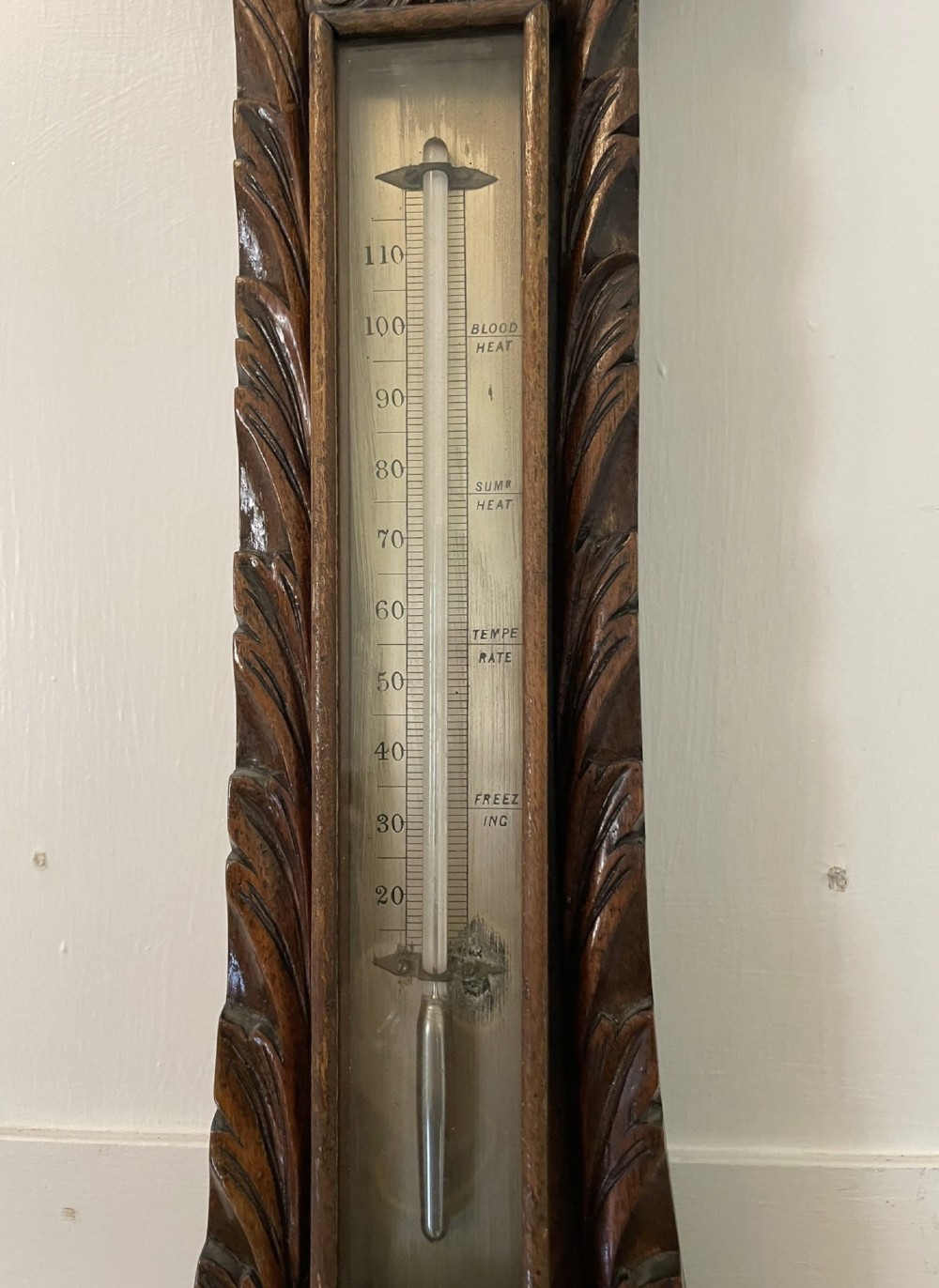 Victorian wall-mounted banjo barometer crafted from carved burr walnut featuring an upper glass thermometer gauge and a lower silvered dial in a brass frame. View VII