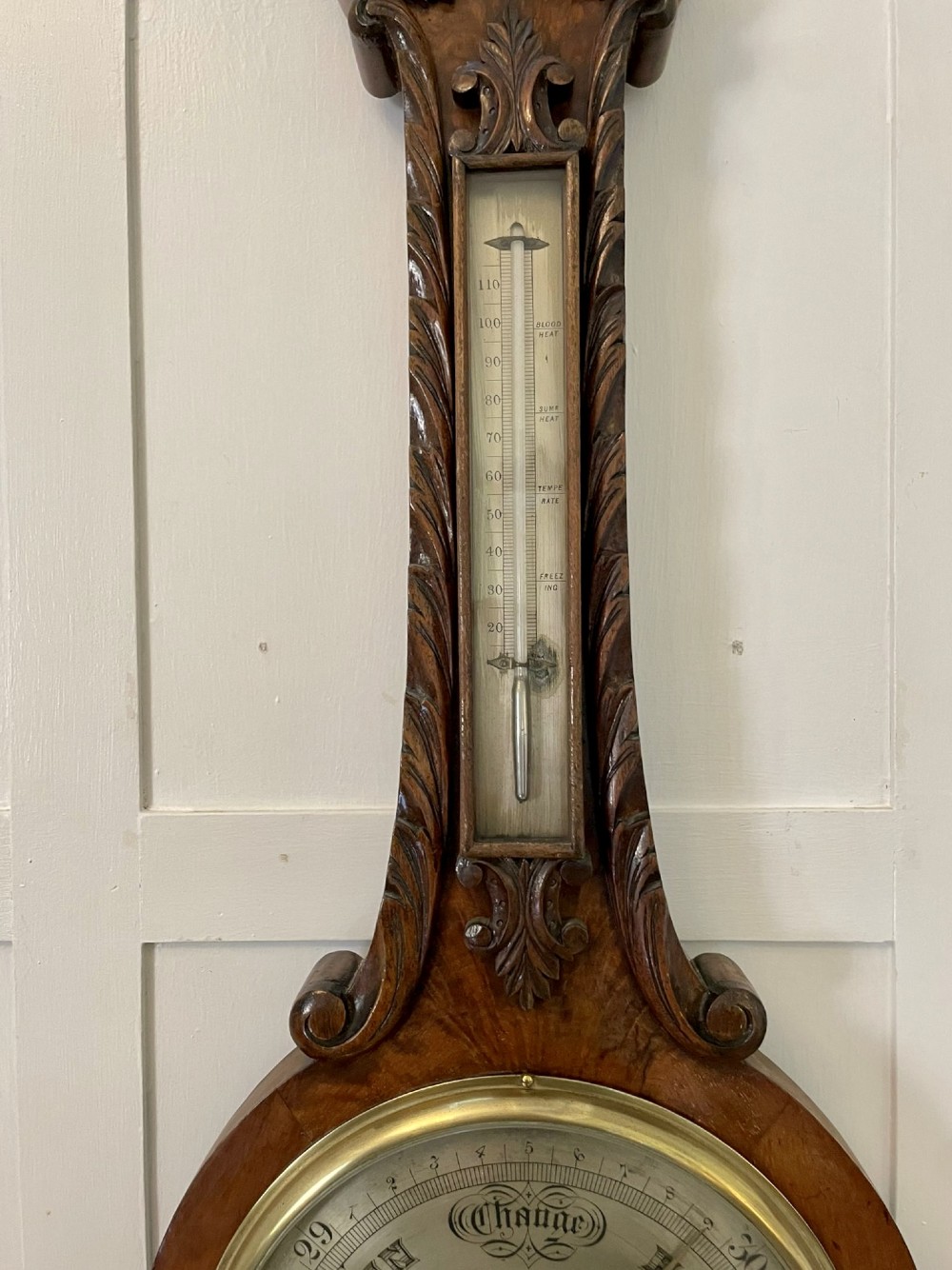 Victorian wall-mounted banjo barometer crafted from carved burr walnut featuring an upper glass thermometer gauge and a lower silvered dial in a brass frame. View IX