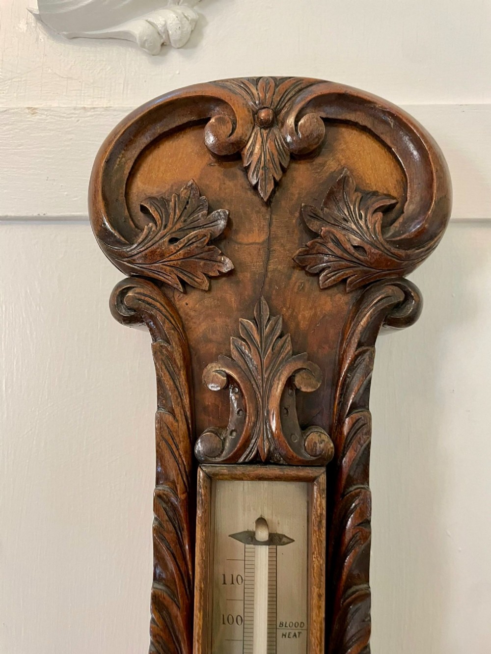 Victorian wall-mounted banjo barometer crafted from carved burr walnut featuring an upper glass thermometer gauge and a lower silvered dial in a brass frame. View X