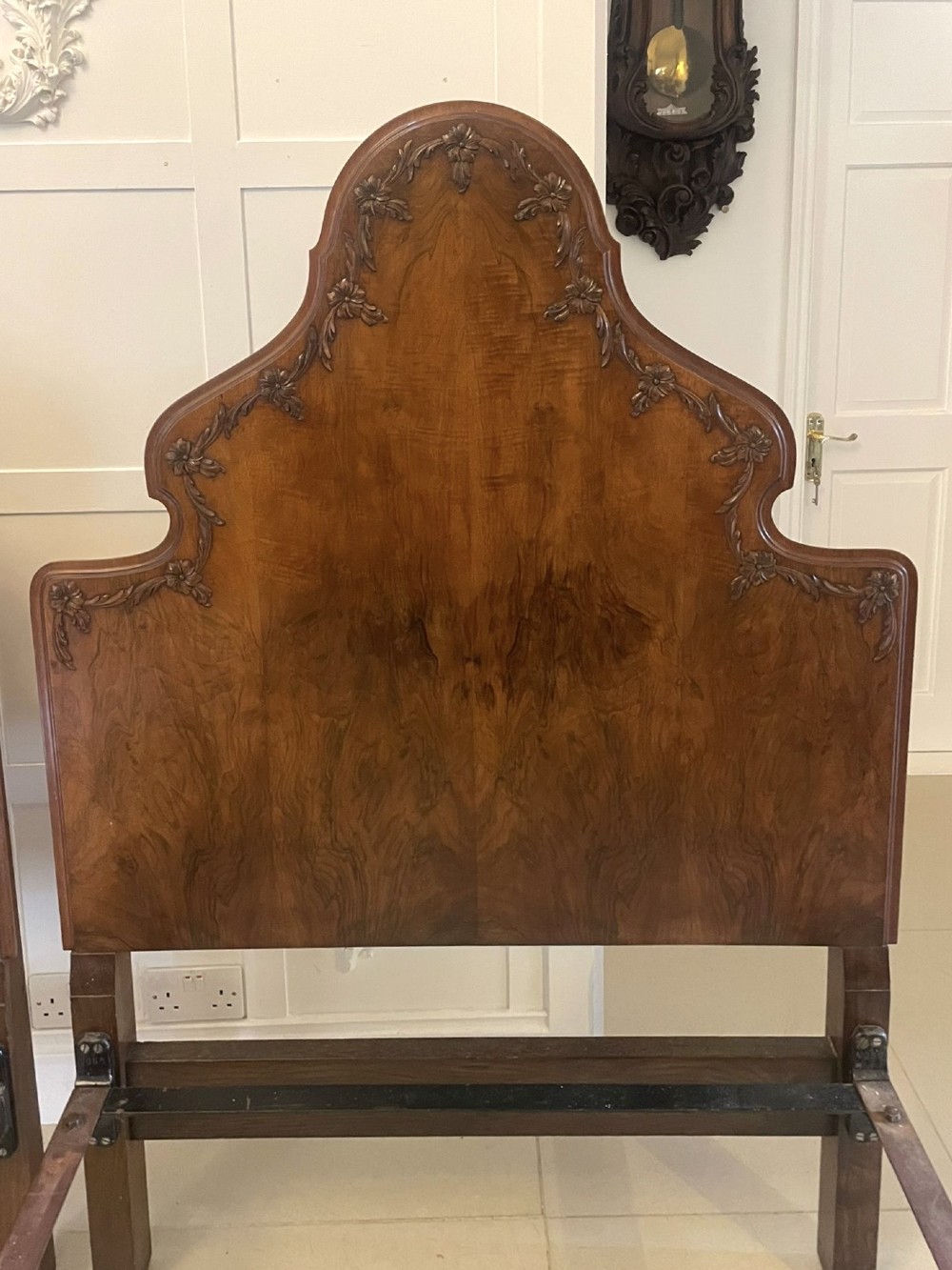 A pair of antique burr walnut single beds featuring high arched headboards, carved shell detailing on the aprons, and scroll-topped footposts. View V