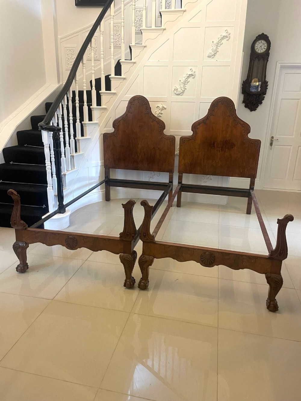 A pair of antique burr walnut single beds featuring high arched headboards, carved shell detailing on the aprons, and scroll-topped footposts. View VII