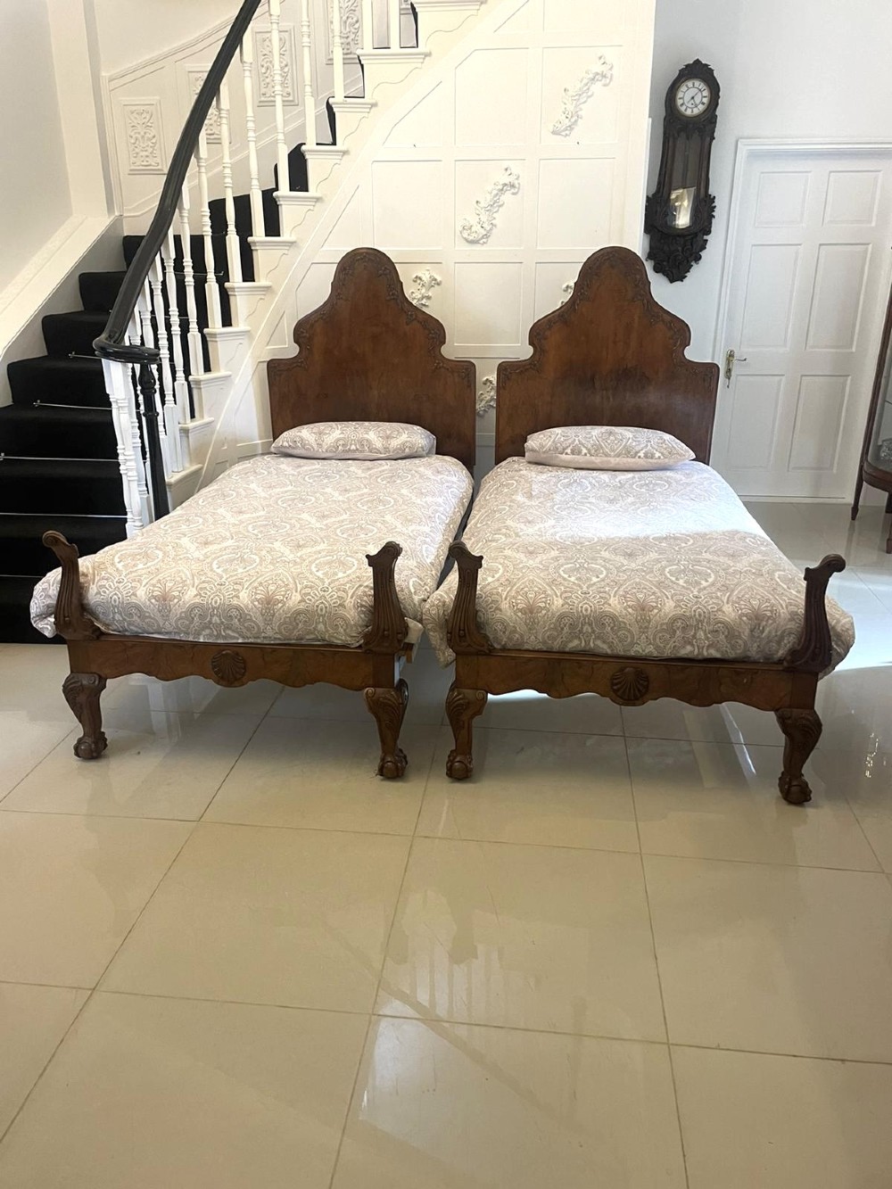 A pair of antique burr walnut single beds featuring high arched headboards, carved shell detailing on the aprons, and scroll-topped footposts. View XV