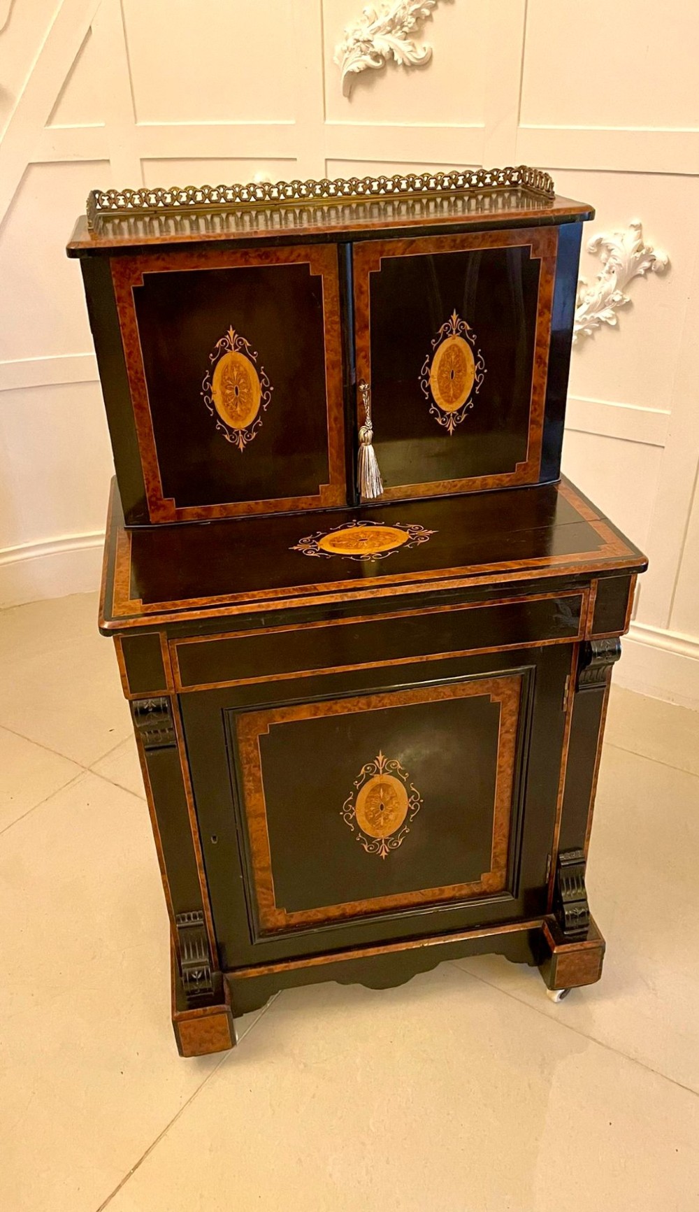 A Victorian ebonised writing desk featuring burr walnut inlaid panels, central oval marquetry medallions, and a pierced brass gallery along the top. View VI