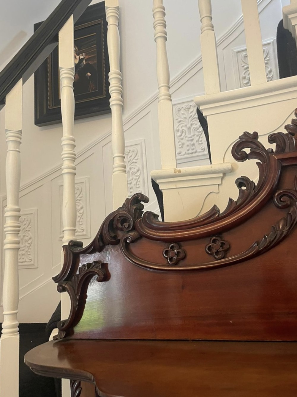 A large Victorian mahogany display cabinet featuring a carved pediment top, central bevelled mirror back, floral satinwood marquetry panel, glazed doors, and a bottom shelf. View IX