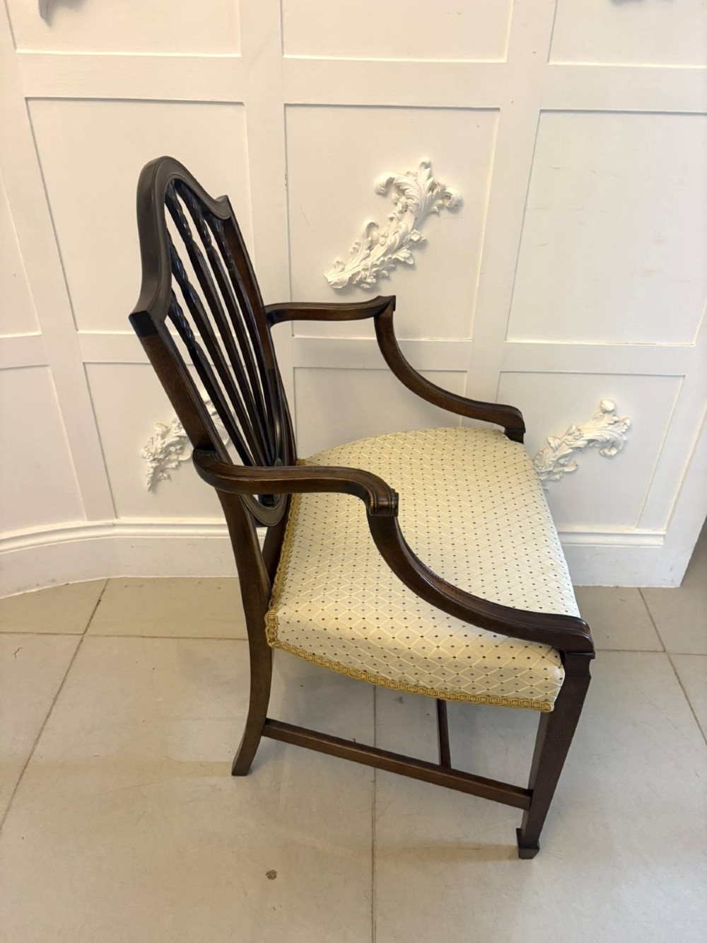 A set of ten antique Edwardian mahogany dining chairs featuring carved shield-shaped backrests and light cream upholstered seats. View IX