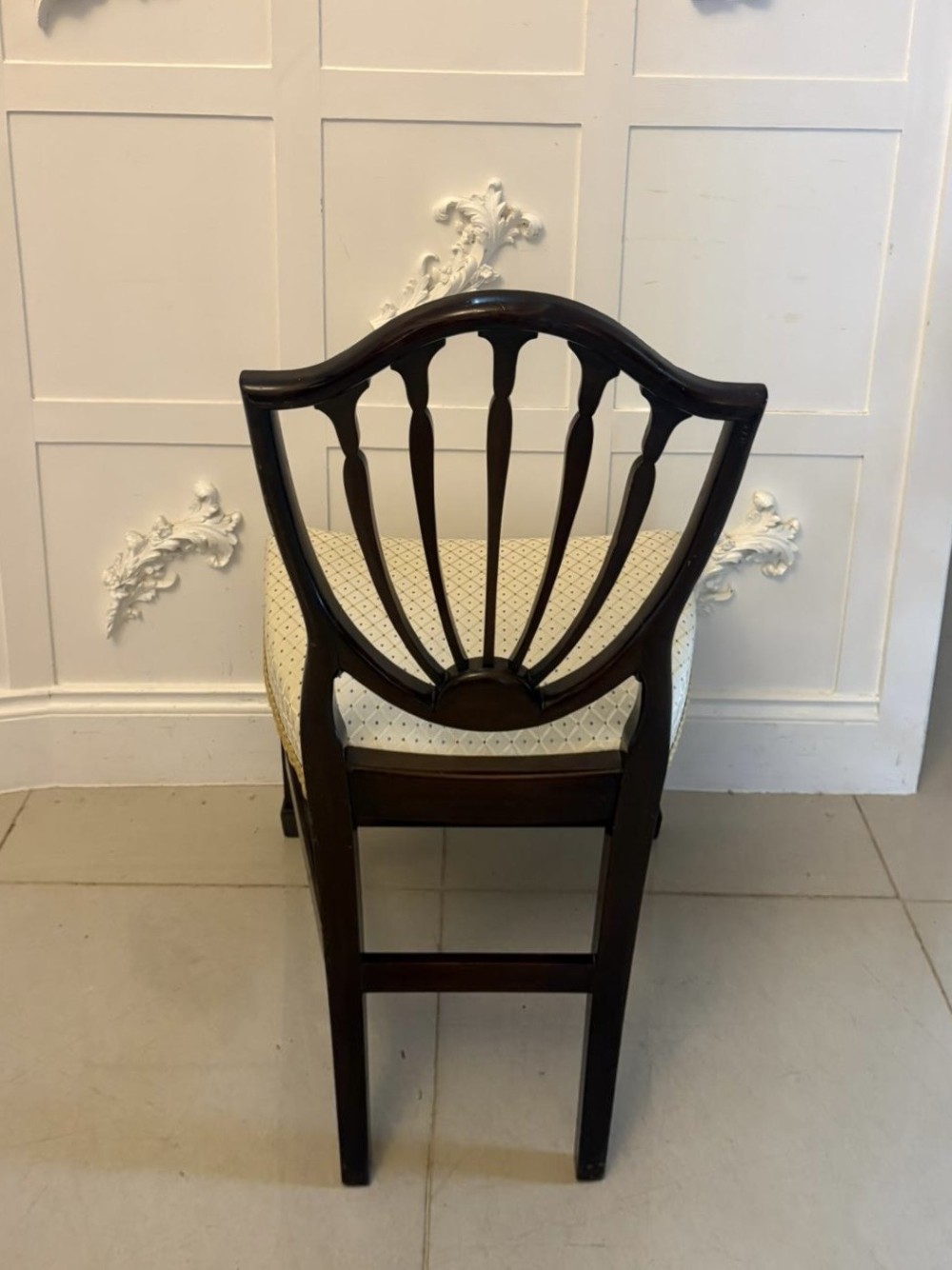 A set of ten antique Edwardian mahogany dining chairs featuring carved shield-shaped backrests and light cream upholstered seats. View X