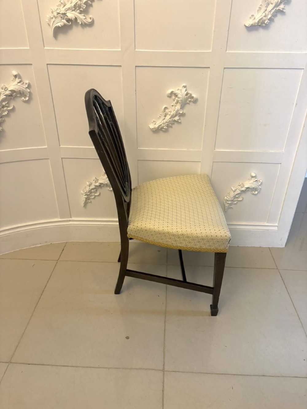 A set of ten antique Edwardian mahogany dining chairs featuring carved shield-shaped backrests and light cream upholstered seats. View XI