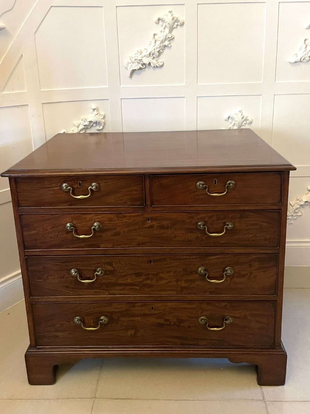 A George III mahogany chest of drawers featuring a two-over-three drawer configuration with brass swan-neck handles on bracket feet. View VI