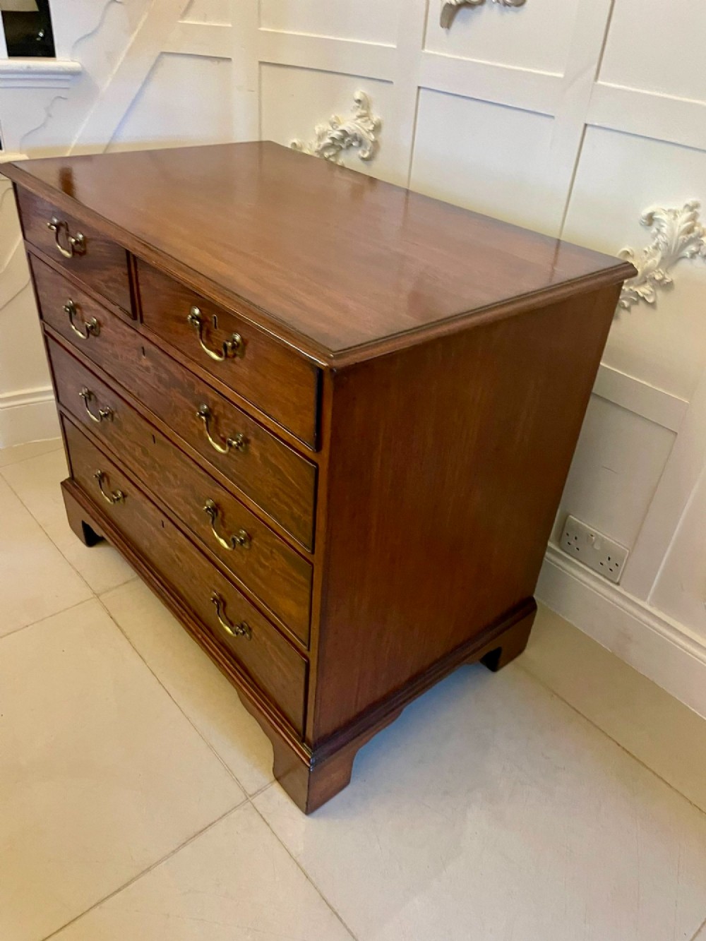 A George III mahogany chest of drawers featuring a two-over-three drawer configuration with brass swan-neck handles on bracket feet. View XI
