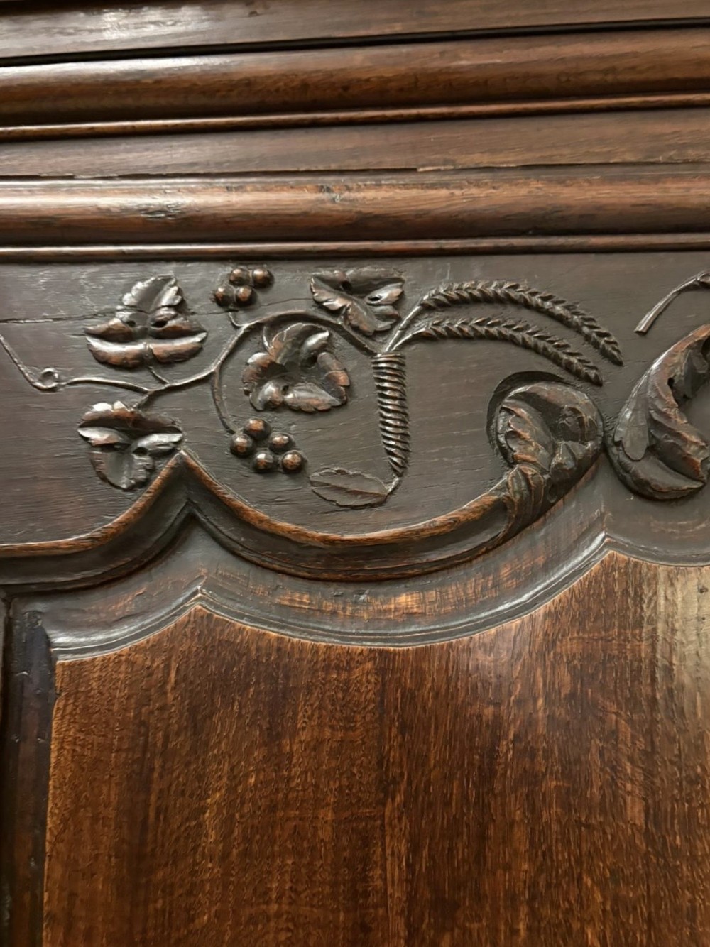 A late 17th-century French Provincial dark oak armoire featuring two panelled doors with relief carvings, long steel hinges, and a moulded top cornice. View VII