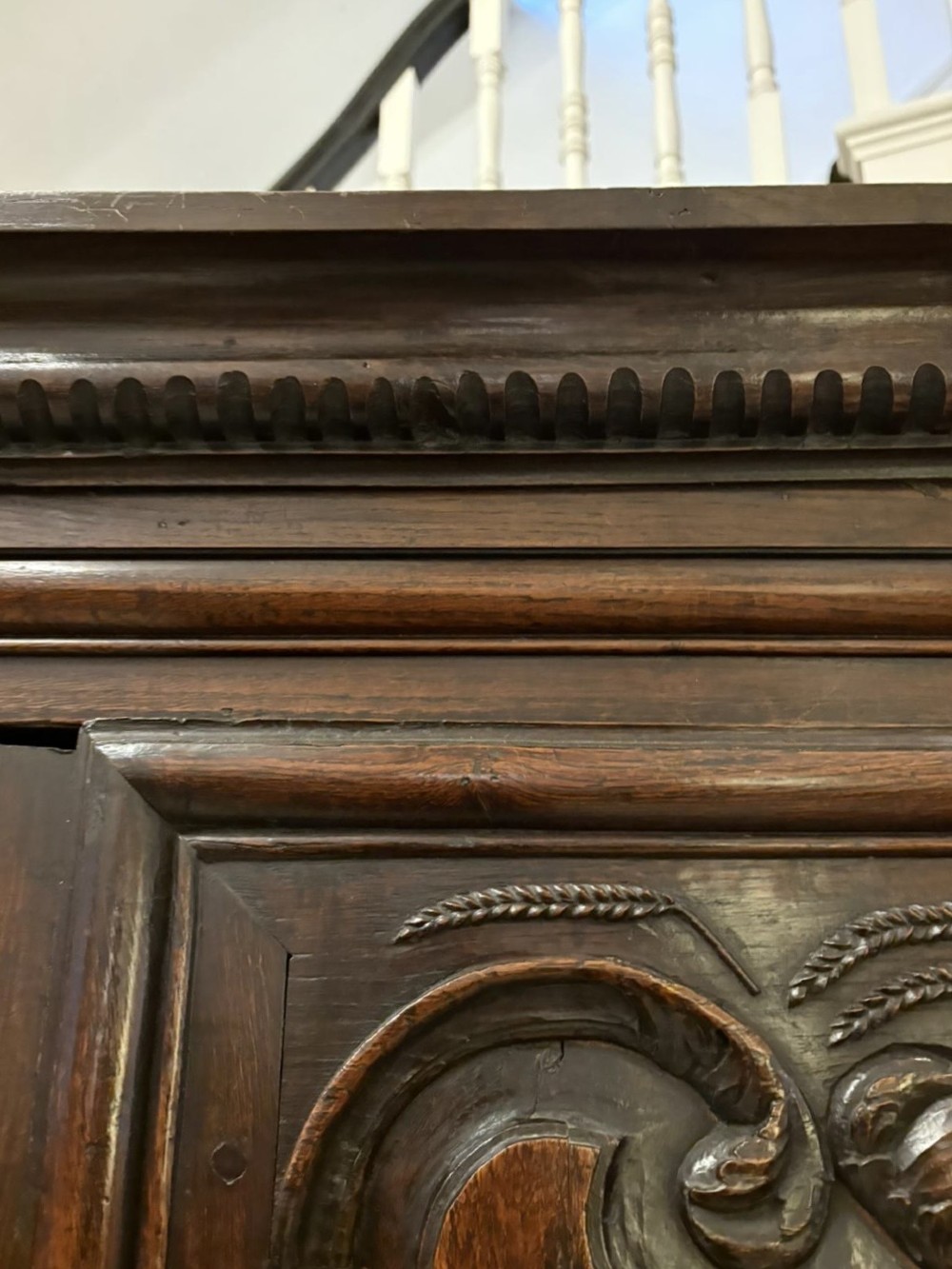 A late 17th-century French Provincial dark oak armoire featuring two panelled doors with relief carvings, long steel hinges, and a moulded top cornice. View X