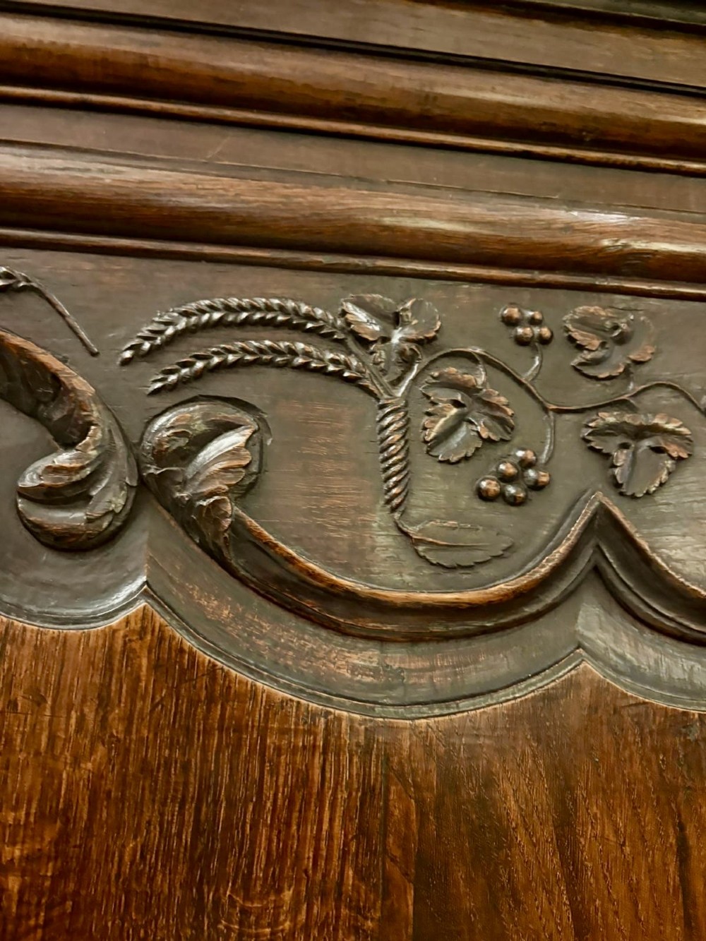 A late 17th-century French Provincial dark oak armoire featuring two panelled doors with relief carvings, long steel hinges, and a moulded top cornice. View XI