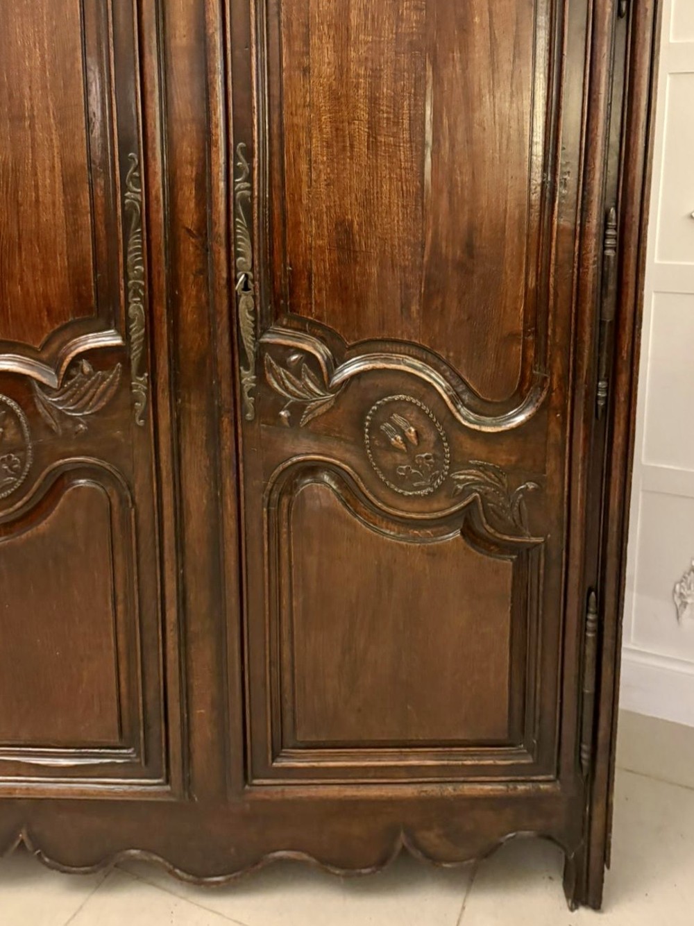 A late 17th-century French Provincial dark oak armoire featuring two panelled doors with relief carvings, long steel hinges, and a moulded top cornice. View XII
