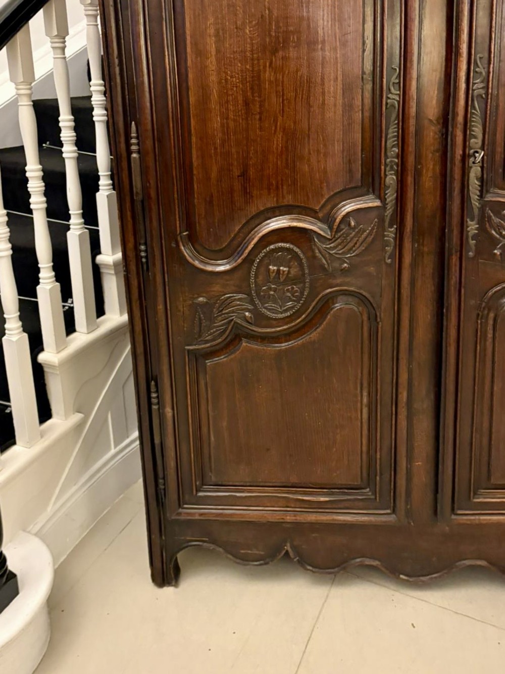 A late 17th-century French Provincial dark oak armoire featuring two panelled doors with relief carvings, long steel hinges, and a moulded top cornice. View XV