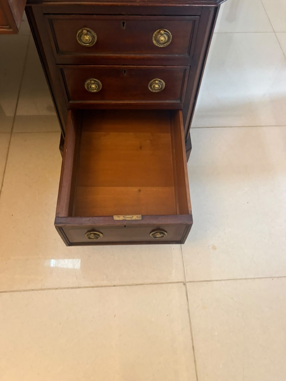 A Victorian mahogany pedestal desk featuring a green leather inset writing surface, brass ring handles, and two drawer pedestals framing a central kneehole. View VI