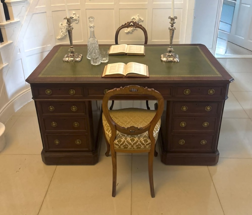 A Victorian mahogany pedestal desk featuring a green leather inset writing surface, brass ring handles, and two drawer pedestals framing a central kneehole. View VIII