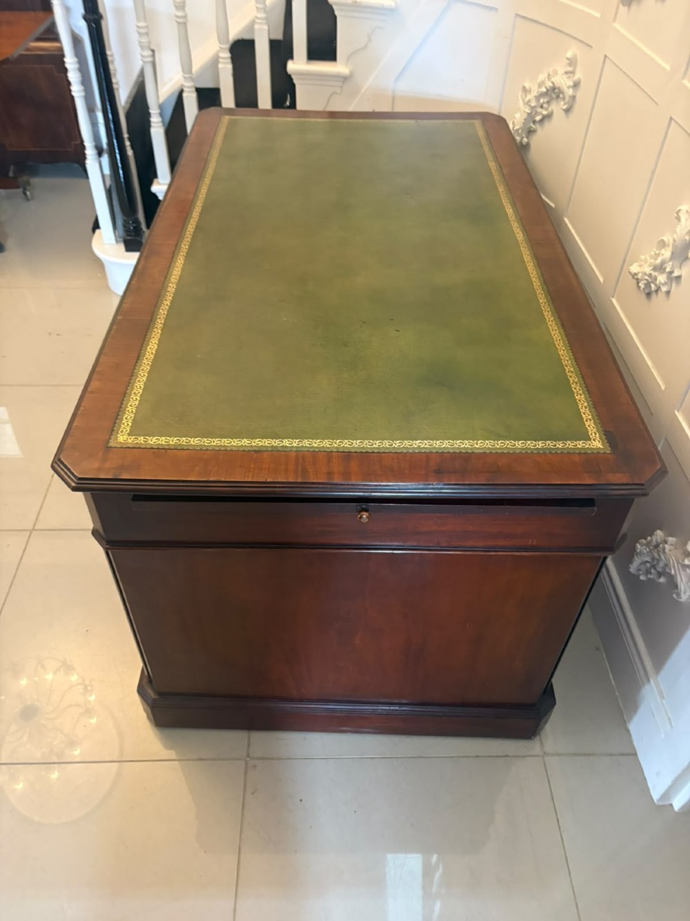 A Victorian mahogany pedestal desk featuring a green leather inset writing surface, brass ring handles, and two drawer pedestals framing a central kneehole. View XI