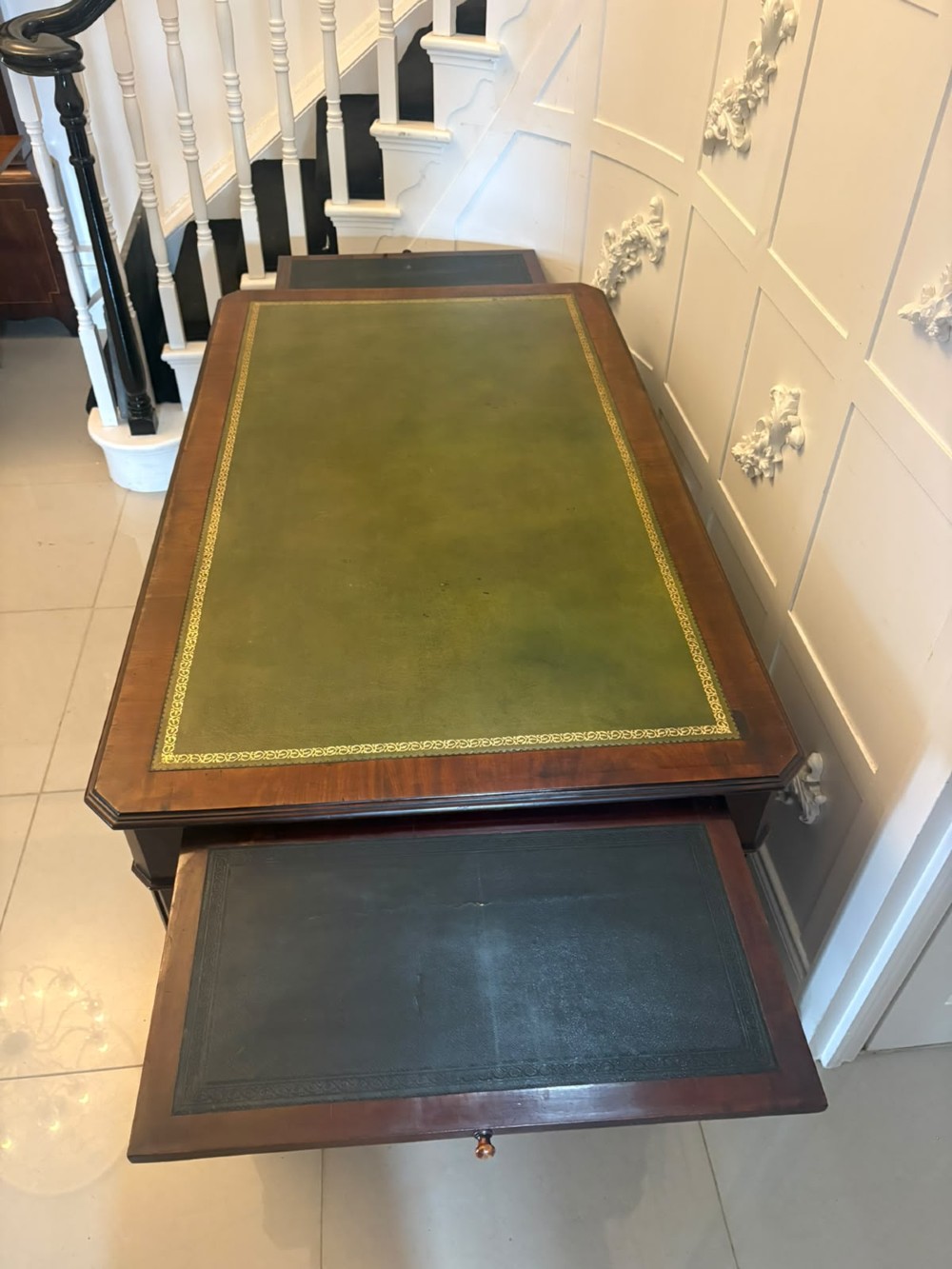 A Victorian mahogany pedestal desk featuring a green leather inset writing surface, brass ring handles, and two drawer pedestals framing a central kneehole. View XII
