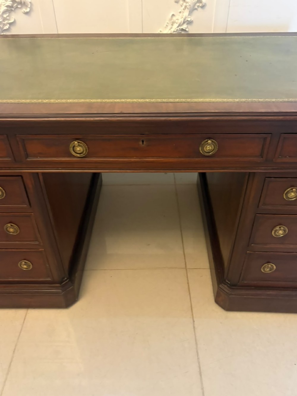 A Victorian mahogany pedestal desk featuring a green leather inset writing surface, brass ring handles, and two drawer pedestals framing a central kneehole. View XIII