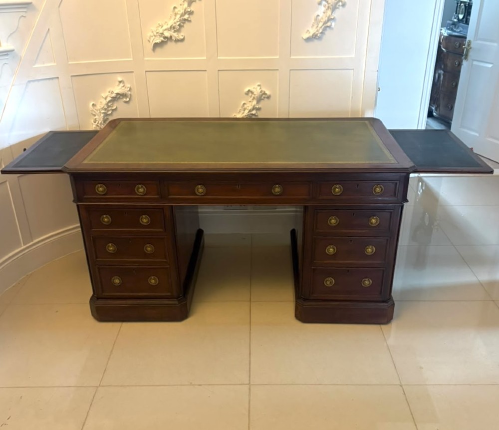 A Victorian mahogany pedestal desk featuring a green leather inset writing surface, brass ring handles, and two drawer pedestals framing a central kneehole. View XIV