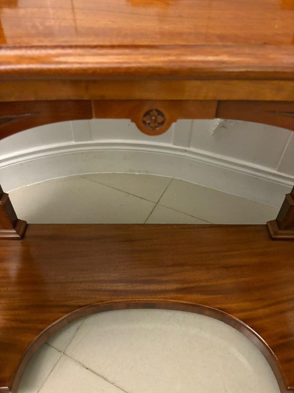 An antique Victorian carved mahogany dressing table featuring an arched swivel mirror, twin trinket drawers, turned front columns, and a shaped lower shelf. View V
