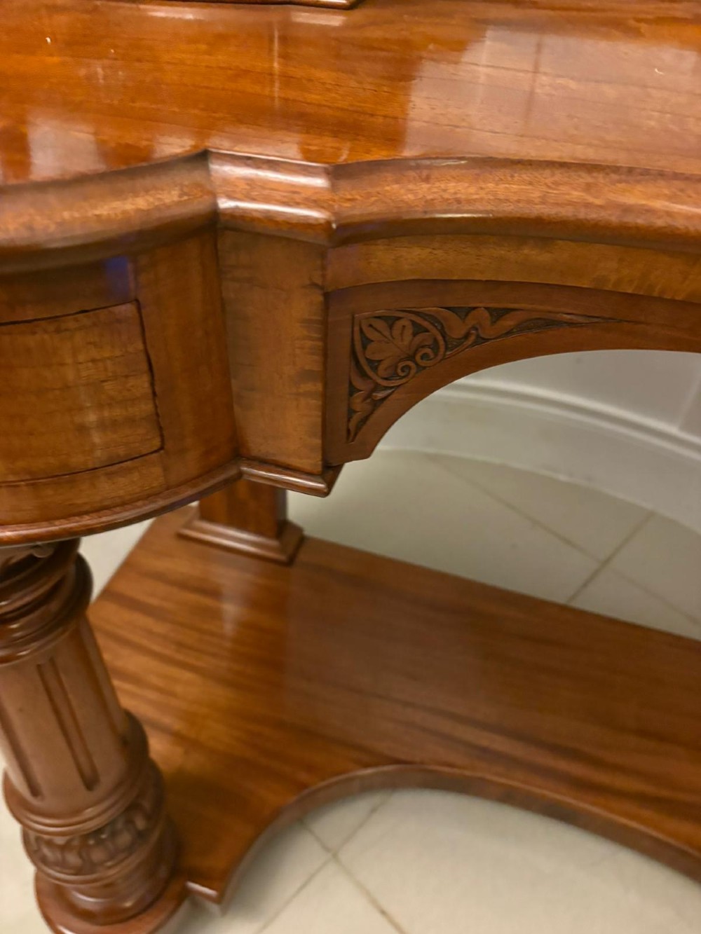 An antique Victorian carved mahogany dressing table featuring an arched swivel mirror, twin trinket drawers, turned front columns, and a shaped lower shelf. View VI