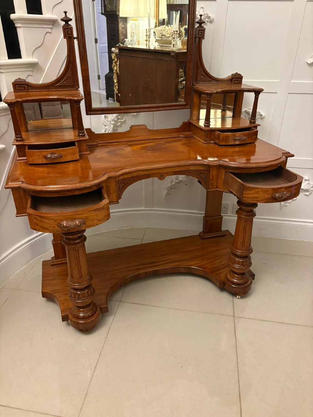 An antique Victorian carved mahogany dressing table featuring an arched swivel mirror, twin trinket drawers, turned front columns, and a shaped lower shelf. View IX