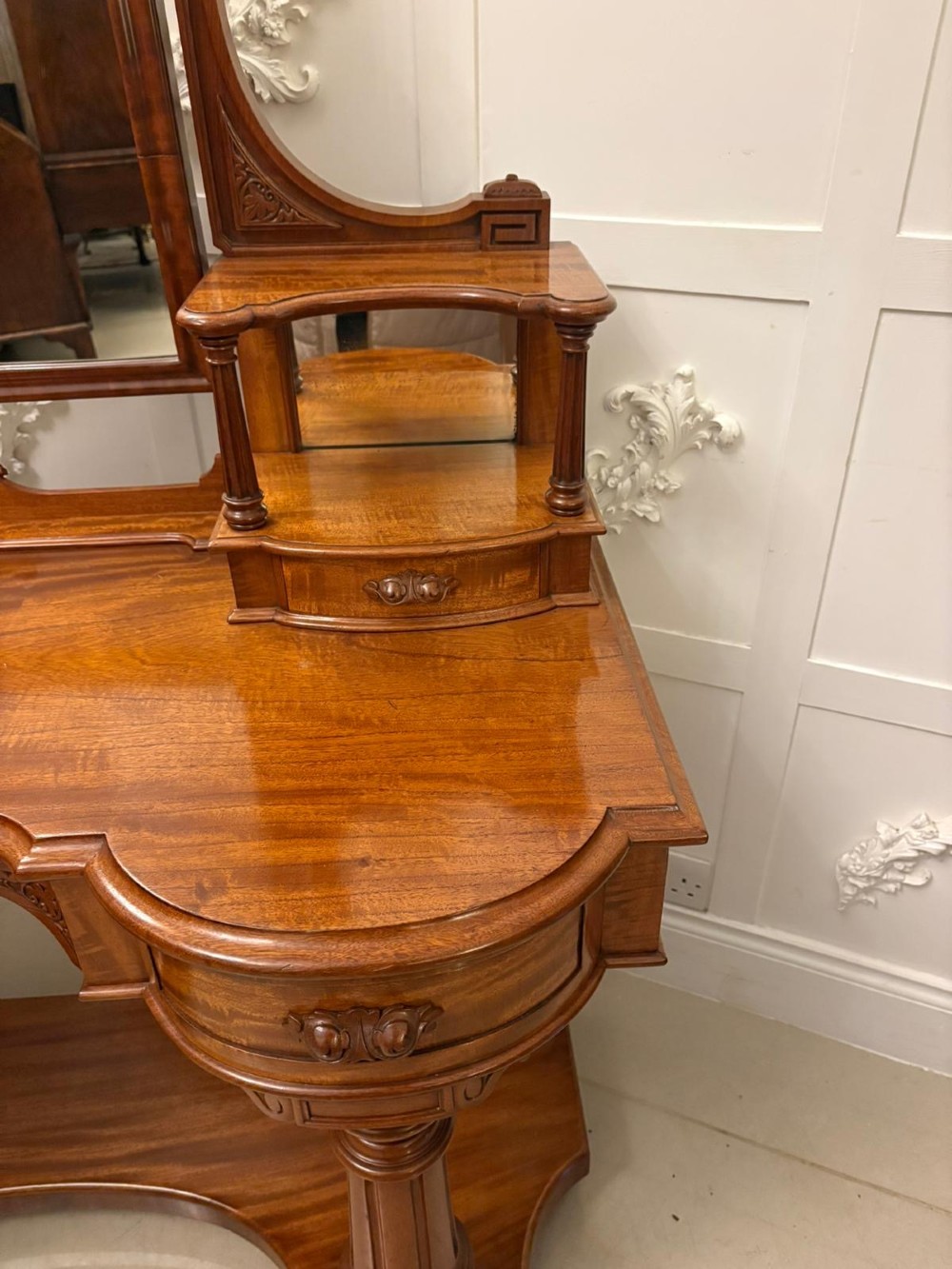 An antique Victorian carved mahogany dressing table featuring an arched swivel mirror, twin trinket drawers, turned front columns, and a shaped lower shelf. View X