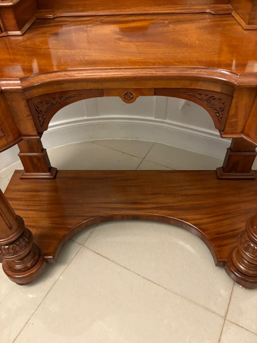 An antique Victorian carved mahogany dressing table featuring an arched swivel mirror, twin trinket drawers, turned front columns, and a shaped lower shelf. View XI