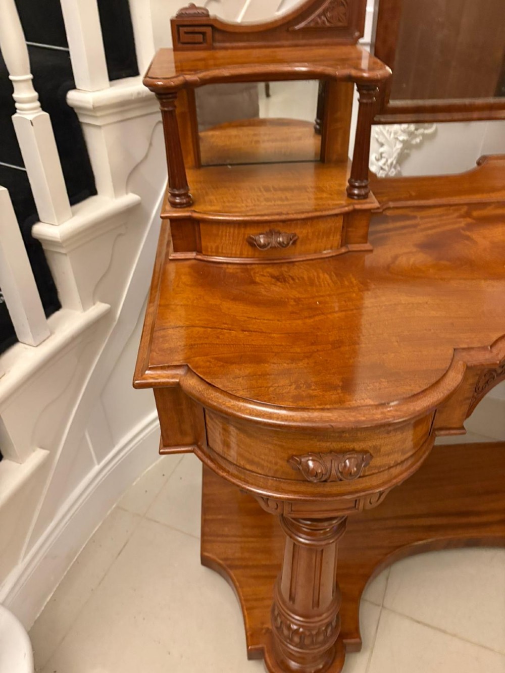 An antique Victorian carved mahogany dressing table featuring an arched swivel mirror, twin trinket drawers, turned front columns, and a shaped lower shelf. View XIII