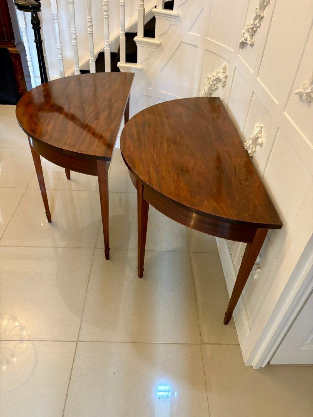 A pair of antique George III semi-circular mahogany console tables with smooth figured tops, apron friezes, and slender tapered legs. View XIV
