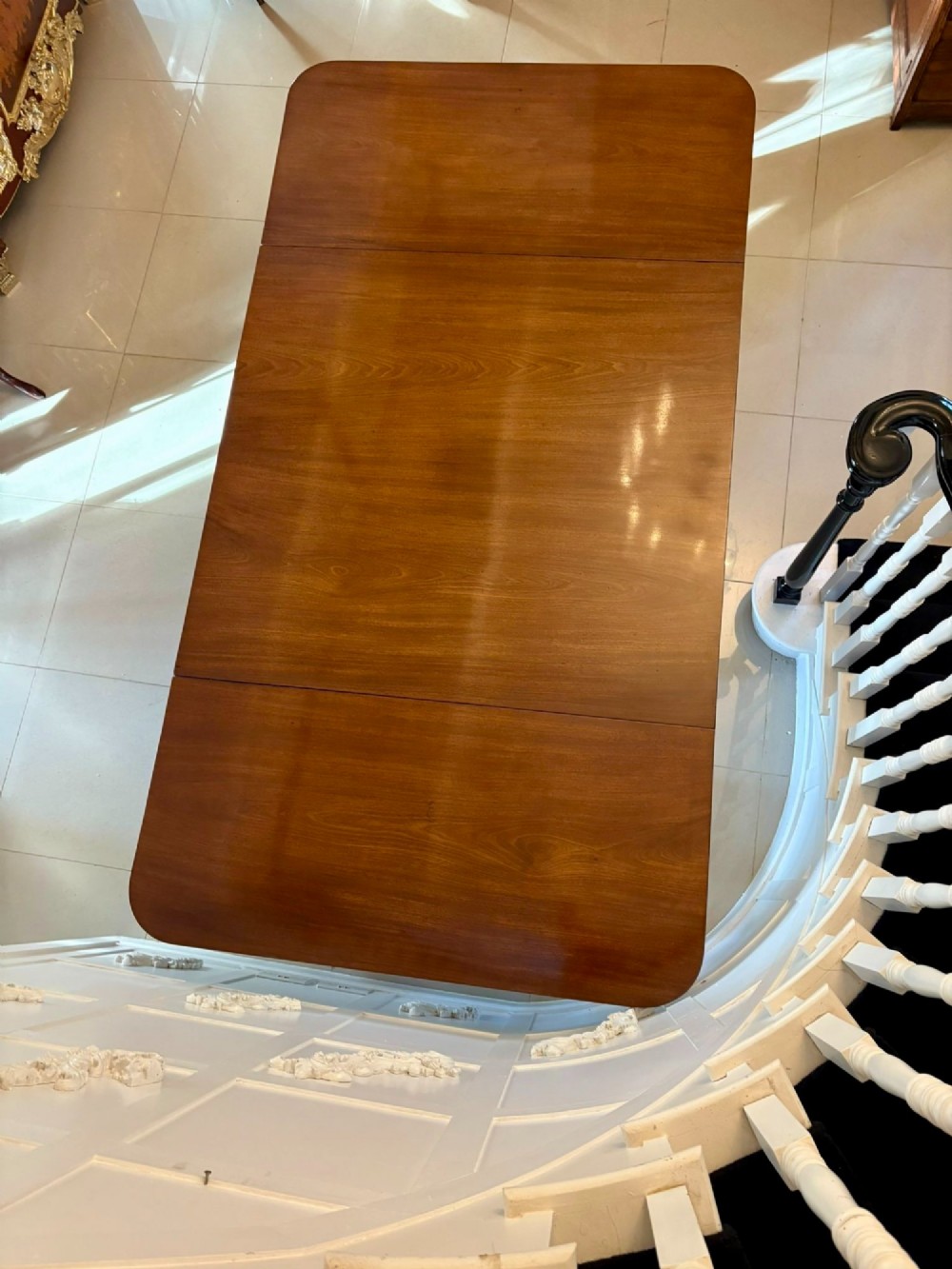 A polished Regency mahogany dining table featuring a three-pillar pedestal base with splayed reeded legs ending in brass castors. View III