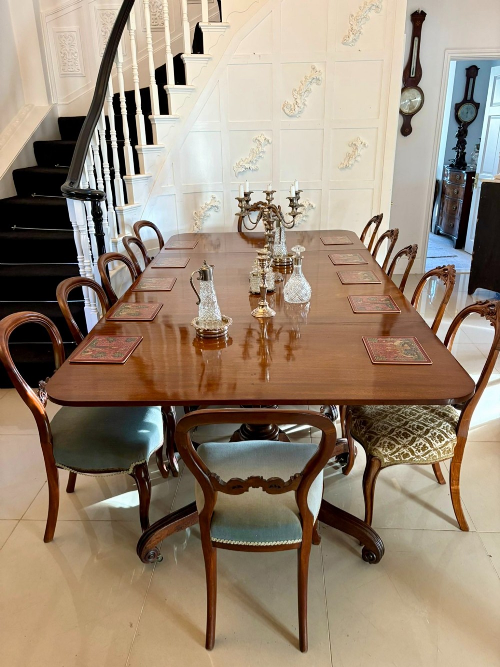 A polished Regency mahogany dining table featuring a three-pillar pedestal base with splayed reeded legs ending in brass castors. View V