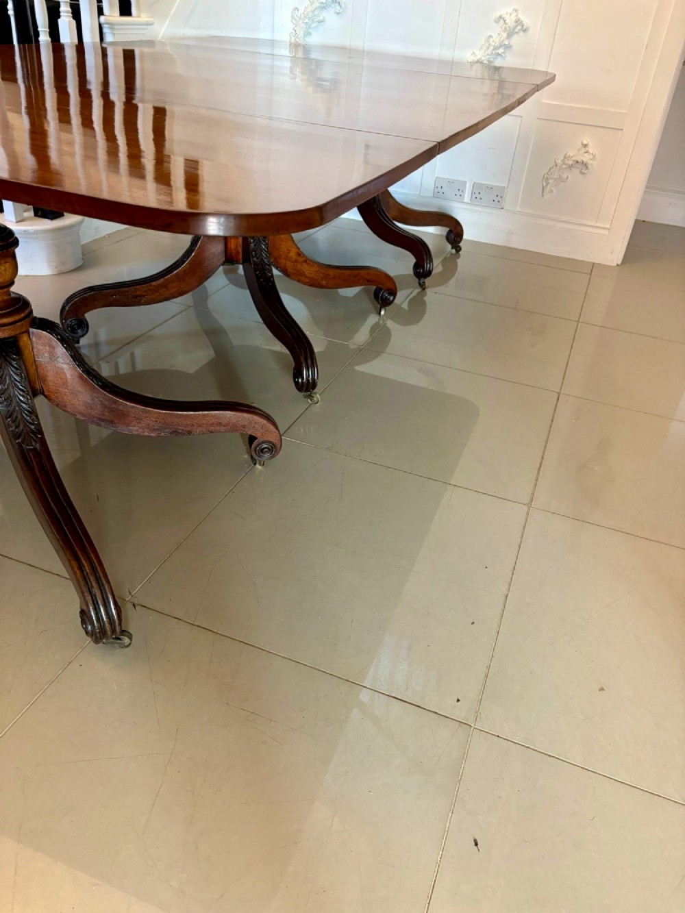 A polished Regency mahogany dining table featuring a three-pillar pedestal base with splayed reeded legs ending in brass castors. View IX