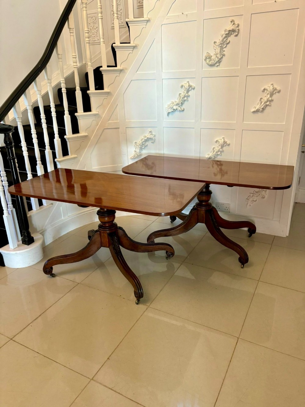 A polished Regency mahogany dining table featuring a three-pillar pedestal base with splayed reeded legs ending in brass castors. View X