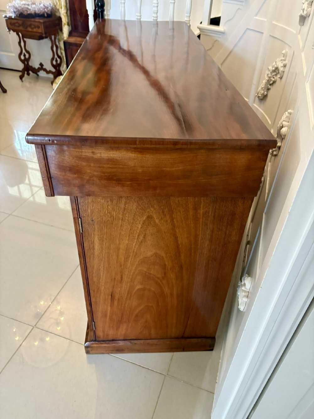 A Victorian figured mahogany sideboard with four arched cupboard doors, three shallow frieze drawers, and a plinth base. View VII