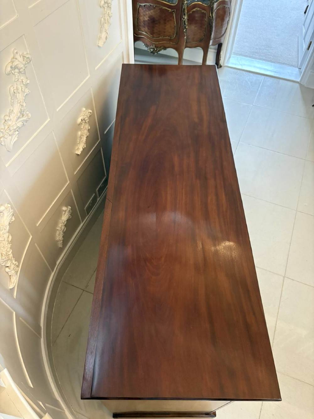 A Victorian figured mahogany sideboard with four arched cupboard doors, three shallow frieze drawers, and a plinth base. View VIII