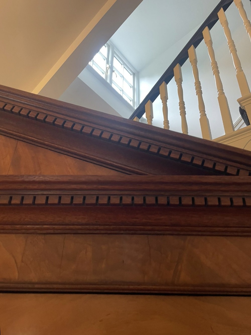 A large George III mahogany breakfront bookcase featuring glazed upper doors topped with a broken swan-neck pediment, set over a base section with drawers and side cupboards. View V