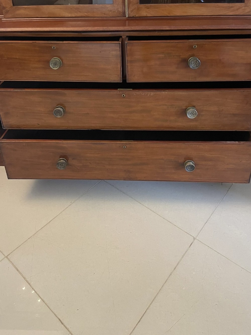 A large George III mahogany breakfront bookcase featuring glazed upper doors topped with a broken swan-neck pediment, set over a base section with drawers and side cupboards. View VIII