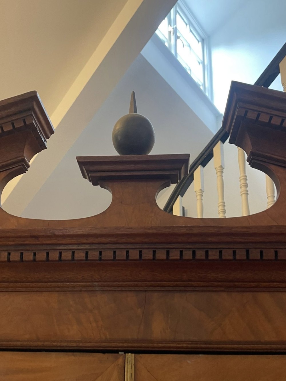 A large George III mahogany breakfront bookcase featuring glazed upper doors topped with a broken swan-neck pediment, set over a base section with drawers and side cupboards. View IX