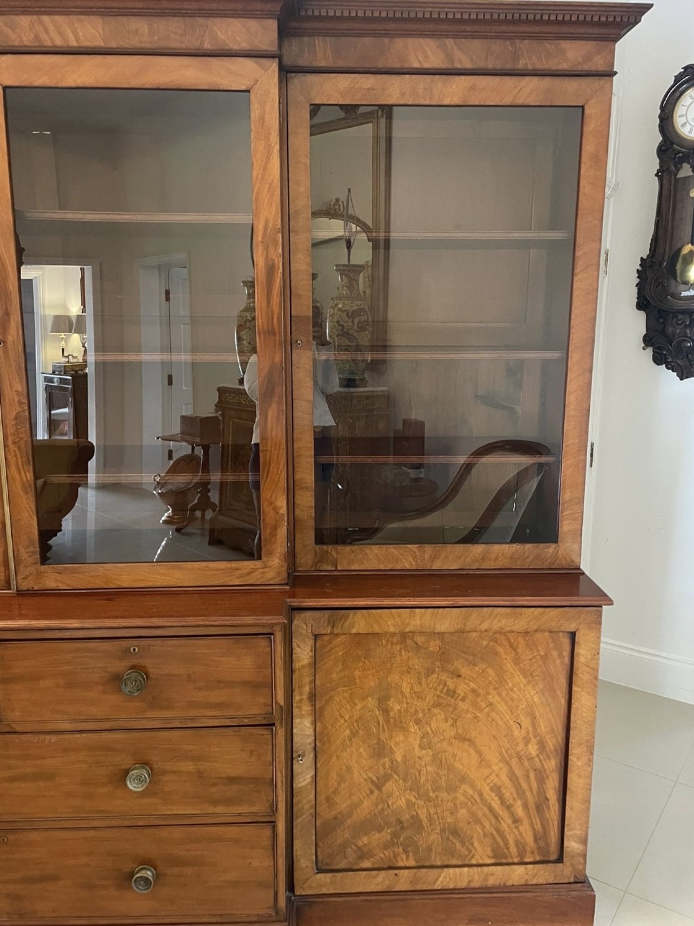 A large George III mahogany breakfront bookcase featuring glazed upper doors topped with a broken swan-neck pediment, set over a base section with drawers and side cupboards. View XIV