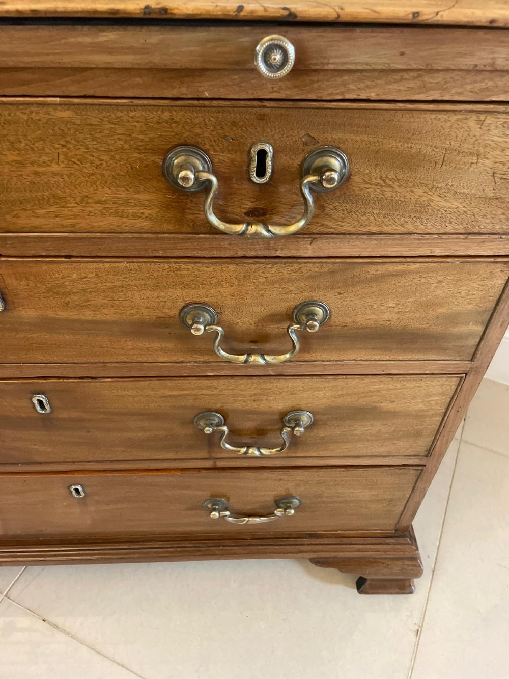 An eighteenth-century George III mahogany chest of drawers featuring a pull-out brushing slide, brass swan-neck handles, and bracket feet. View II