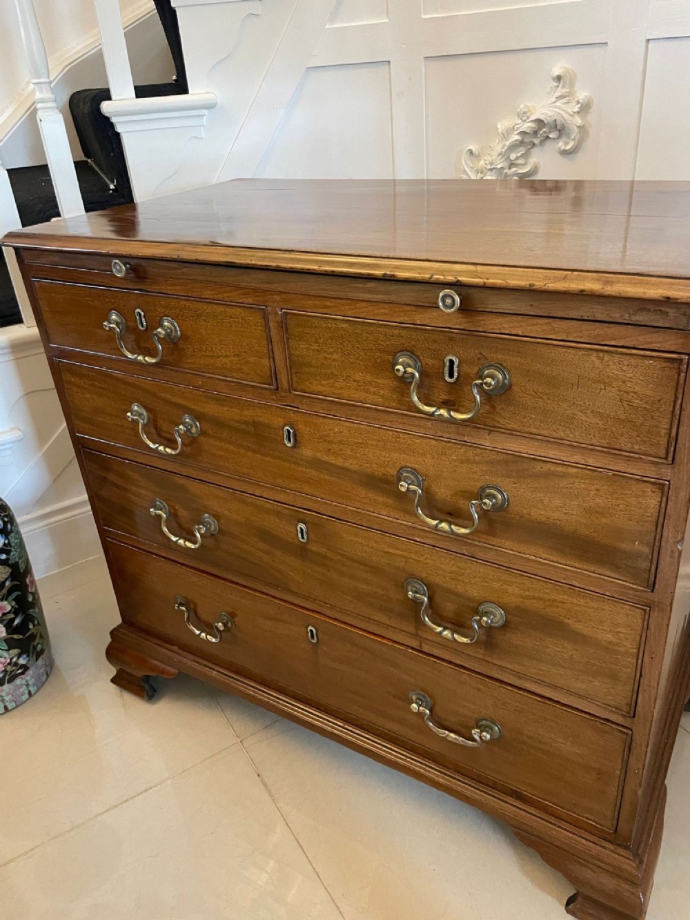 An eighteenth-century George III mahogany chest of drawers featuring a pull-out brushing slide, brass swan-neck handles, and bracket feet. View IV