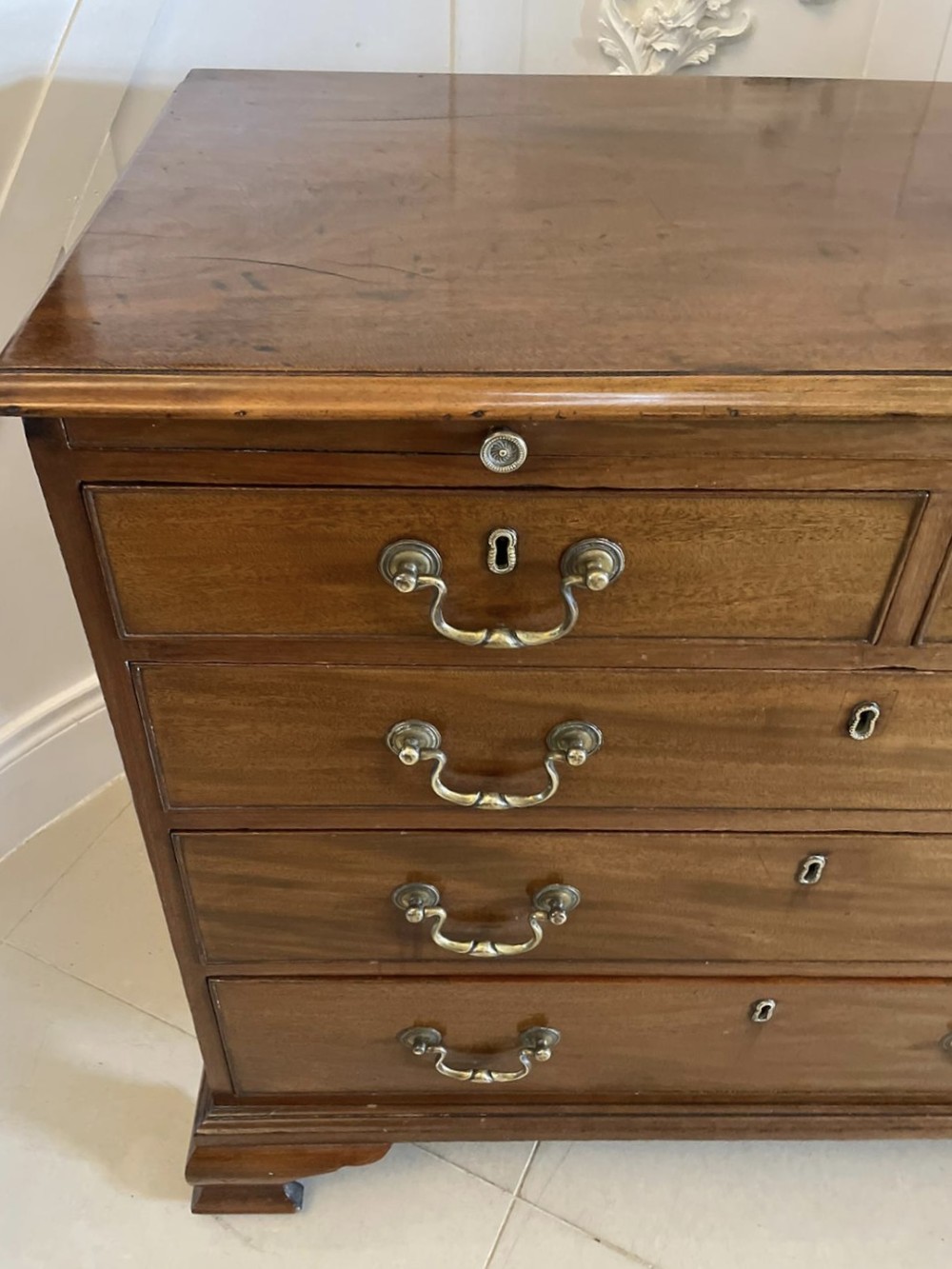An eighteenth-century George III mahogany chest of drawers featuring a pull-out brushing slide, brass swan-neck handles, and bracket feet. View IX
