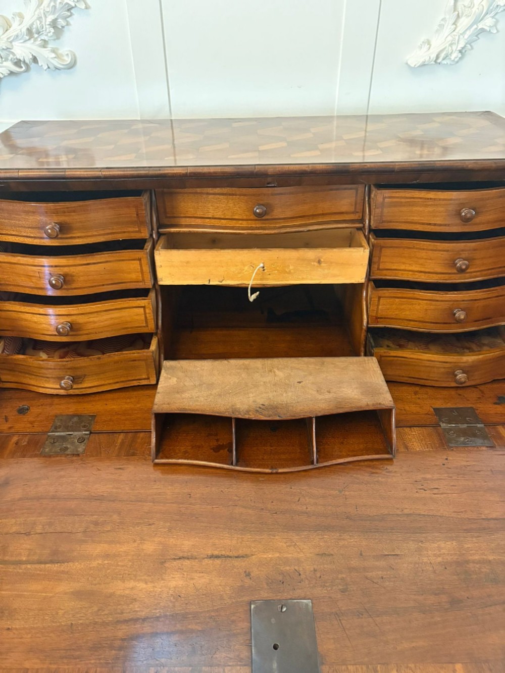 An 18th-century French walnut bureau featuring geometric cubic parquetry inlay, a sloped fall-front lid, curved bombe sides, and brass handles. View IV